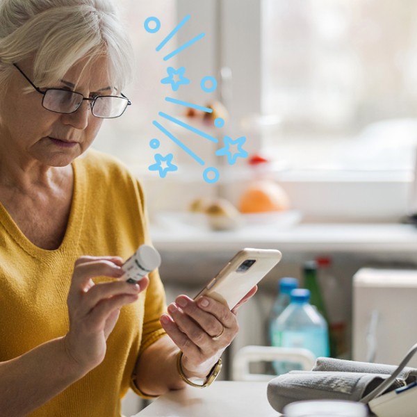 Frau in orangem Oberteil sitzt vor dem Handy