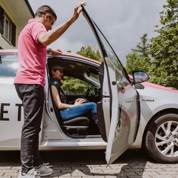 Ein Mann hilft einer Frau beim Einsteigen in ein Auto.